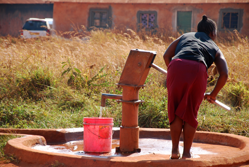 African woman pumping water from a water well