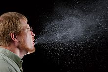 Man sneezing with airborne particles coming from his mouth.